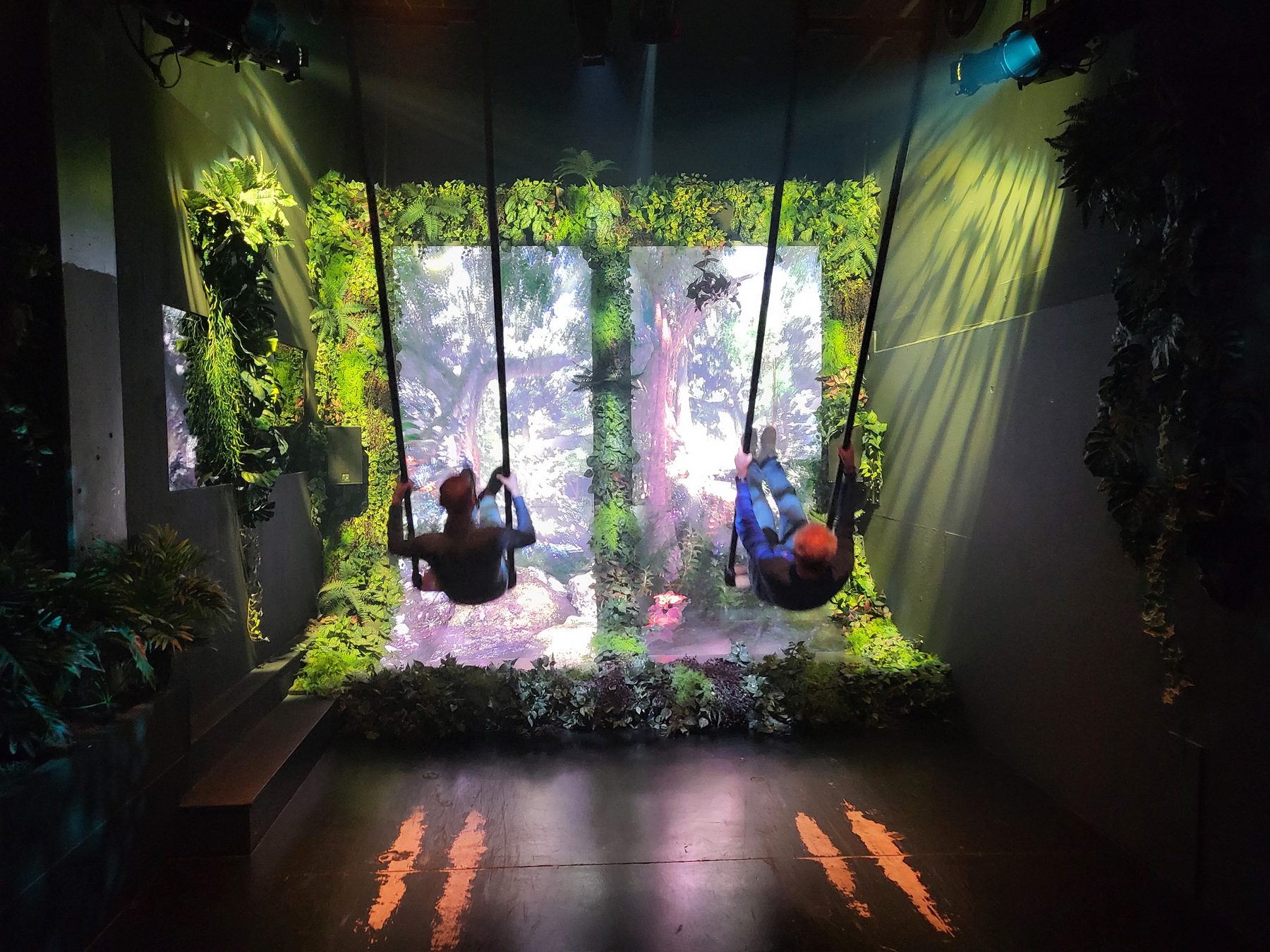 Een collega staat op een podium in magenta en paars licht, tussen planten.
