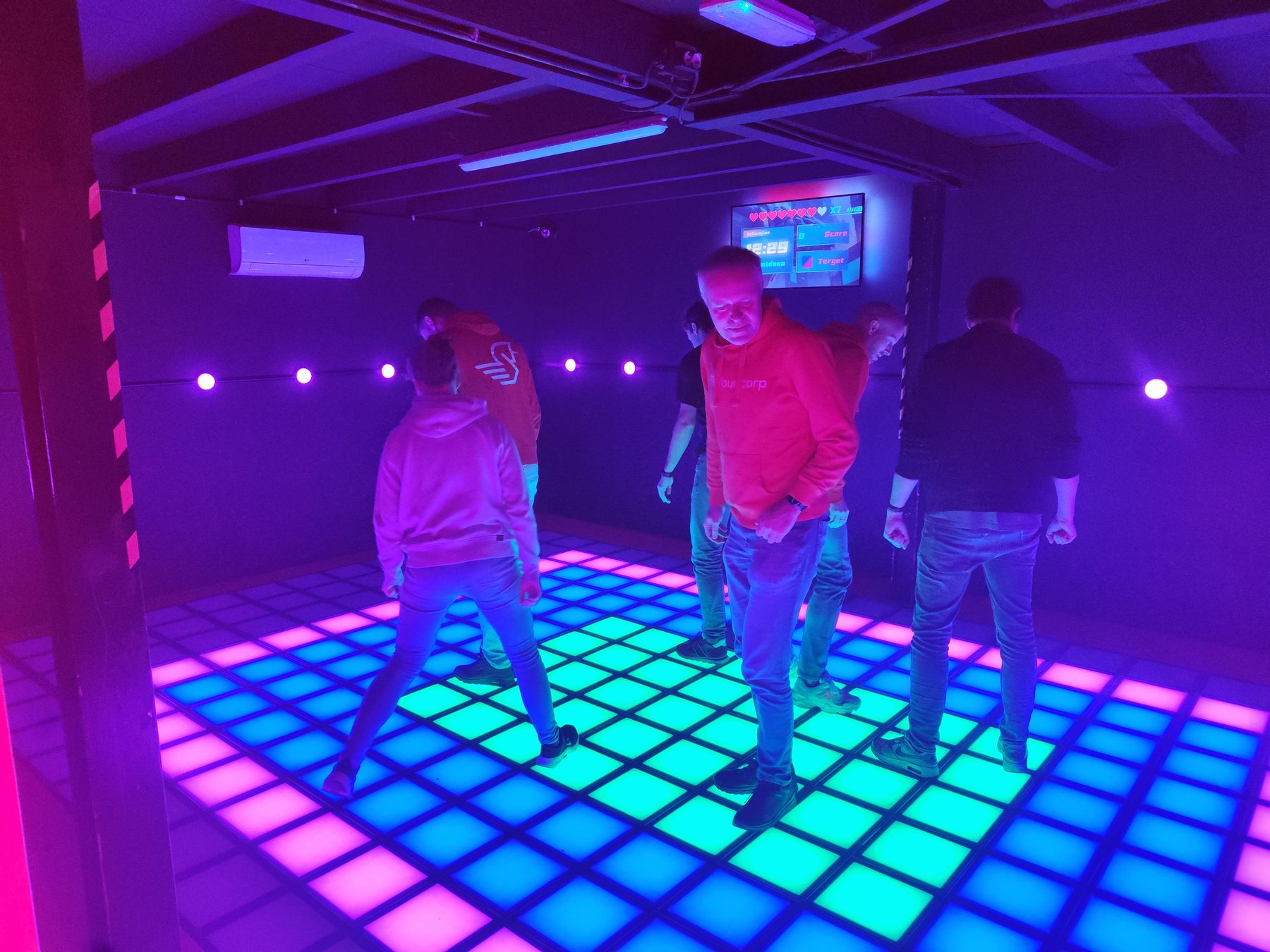 Collega's op een verlichte dansvloer in paars en roze licht.
