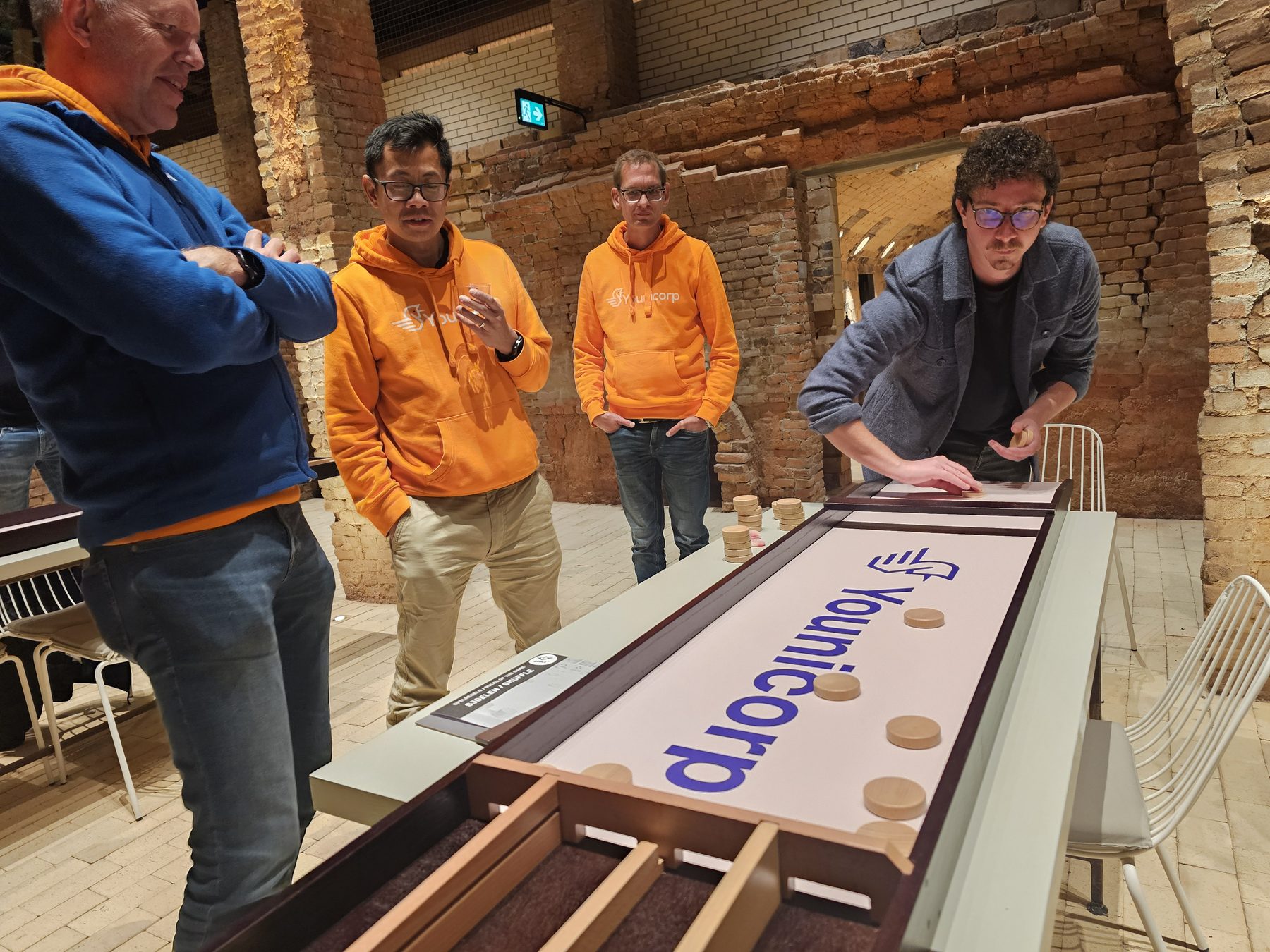 Collega's spelen op een sjoelbak met het Younicorp-logo erop.