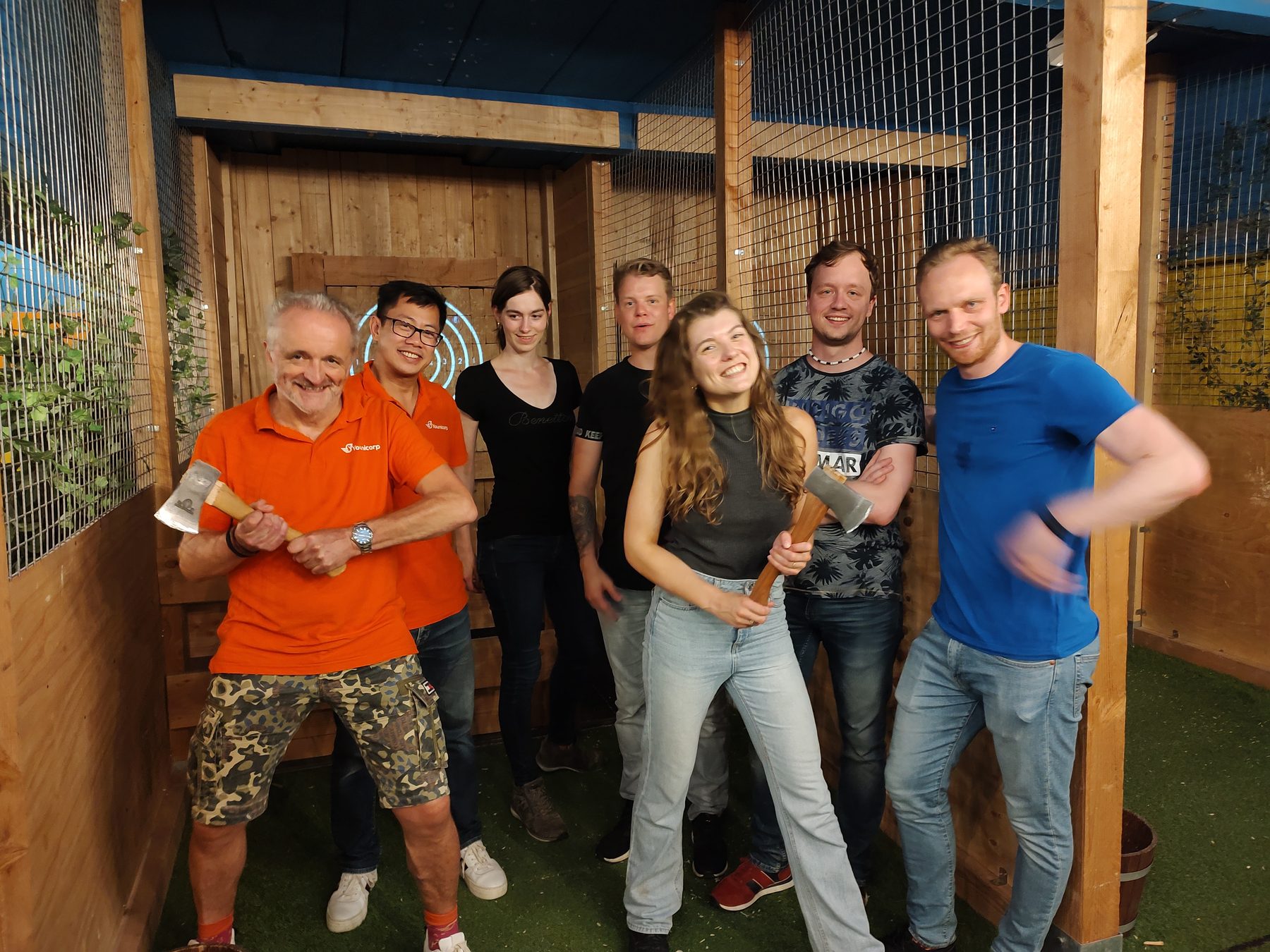 Het team poseert lachend met bijlen in de hand na het bijlwerpen.