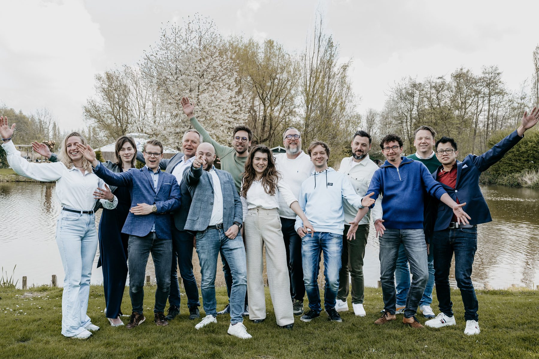Het team van Younicorp juicht met de armen omhoog, buiten aan het water.
