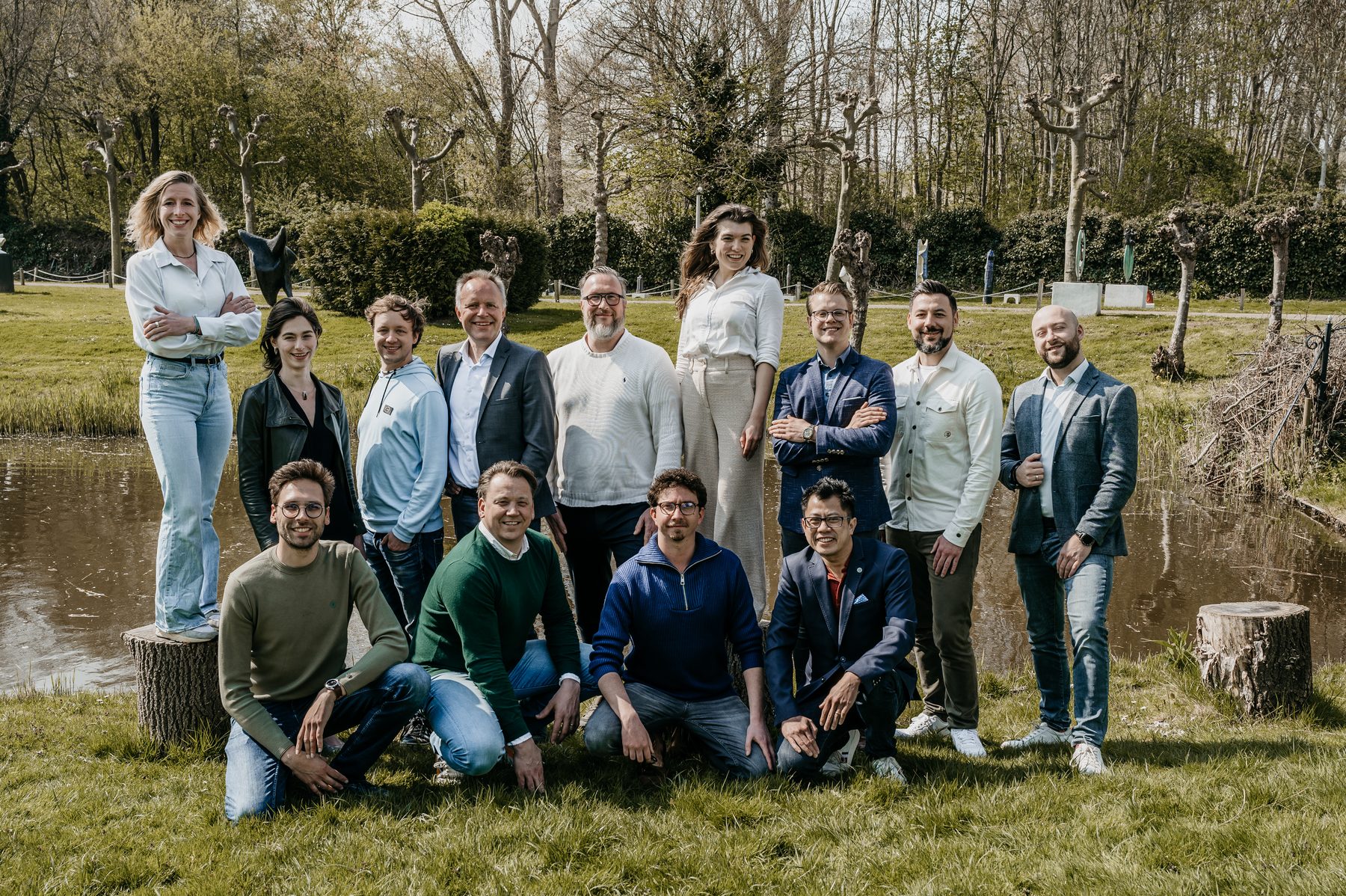 Het voltallige team van Younicorp poseert buiten aan het water op een landgoed, in het voorjaar.