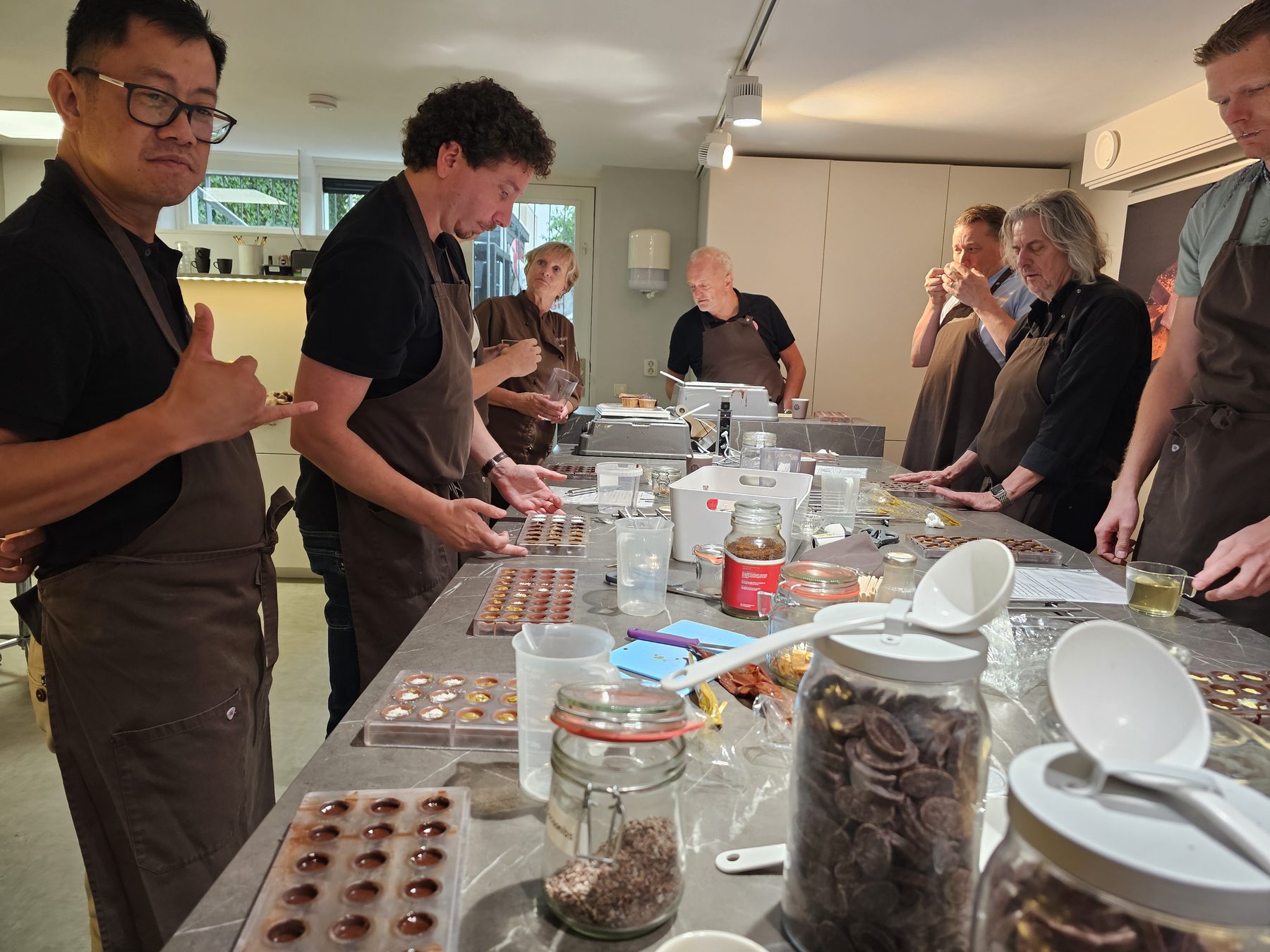 Collega's in schorten maken bonbons aan een lange werkbank in een chocolade-atelier.