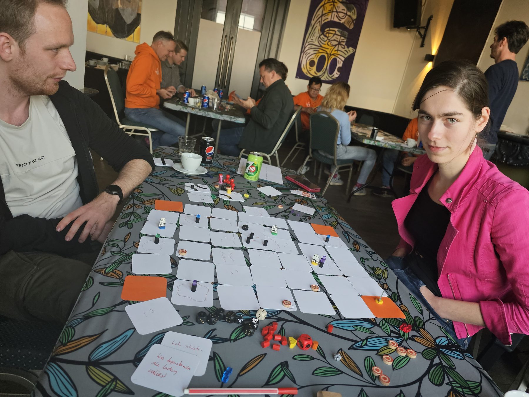 Drie collega's spelen een serious game met kaarten op een grote tafel.