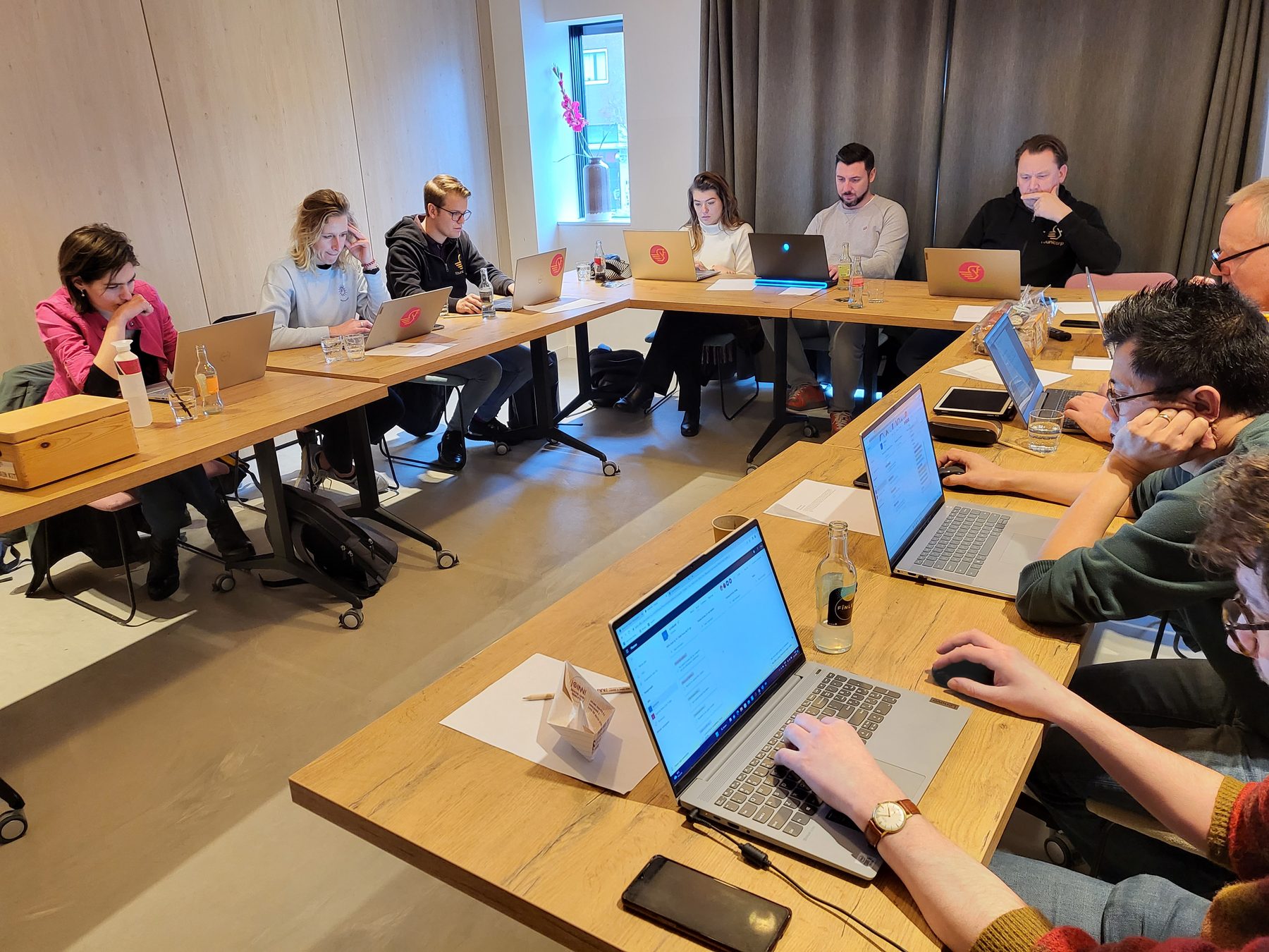 Collega's werken op laptops aan lange tafels tijdens een Epic Friday; op het scherm staat Epic Friday.